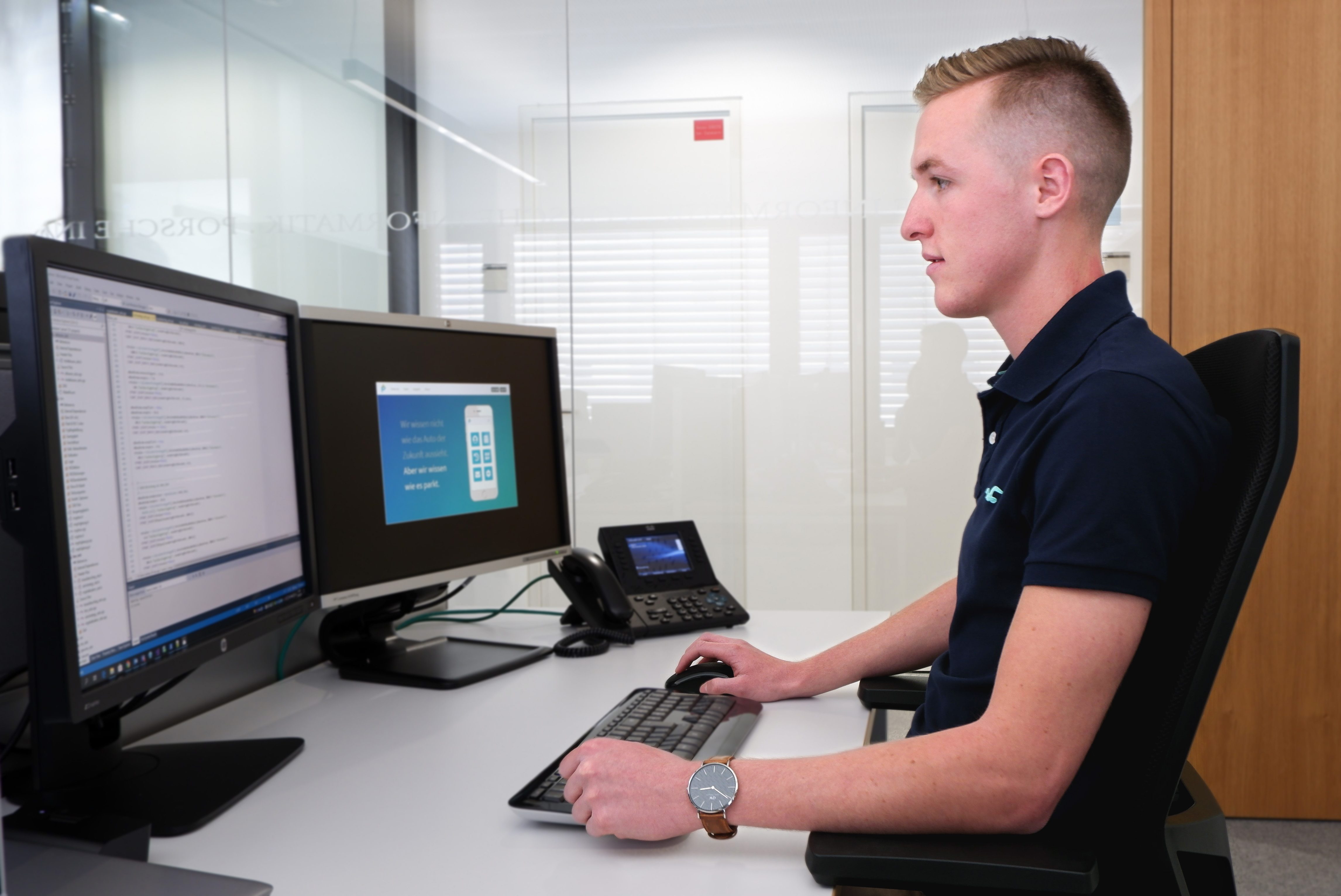 Intern Stefan sitting at his workplace at Porsche Informatik.